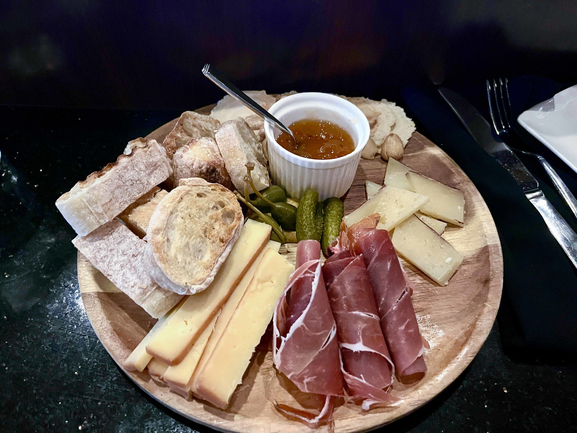 charcuterie plate with sliced meat and cheese and container of honey